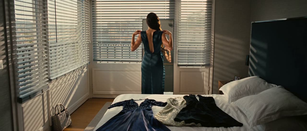 A woman choosing between gowns in a hotel room